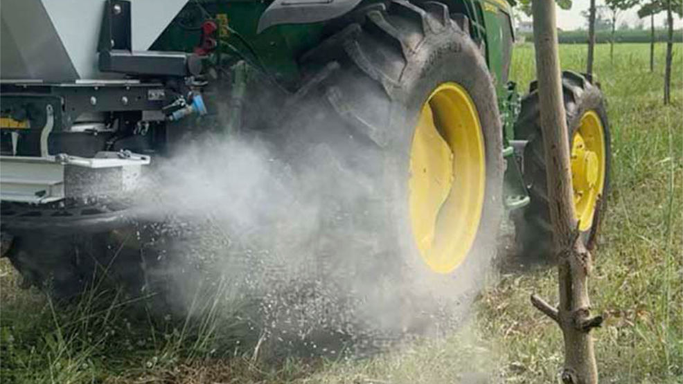 Tractor spreading fertilizer in a field with Eurospand machinery.